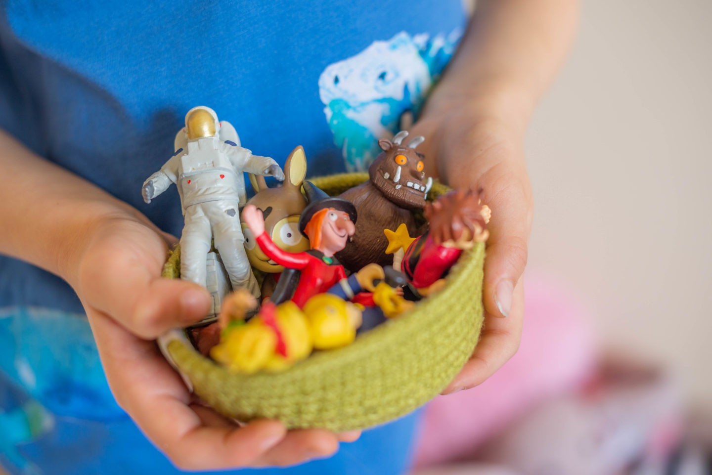 Toniebox Figures held in a basket by children's hands.