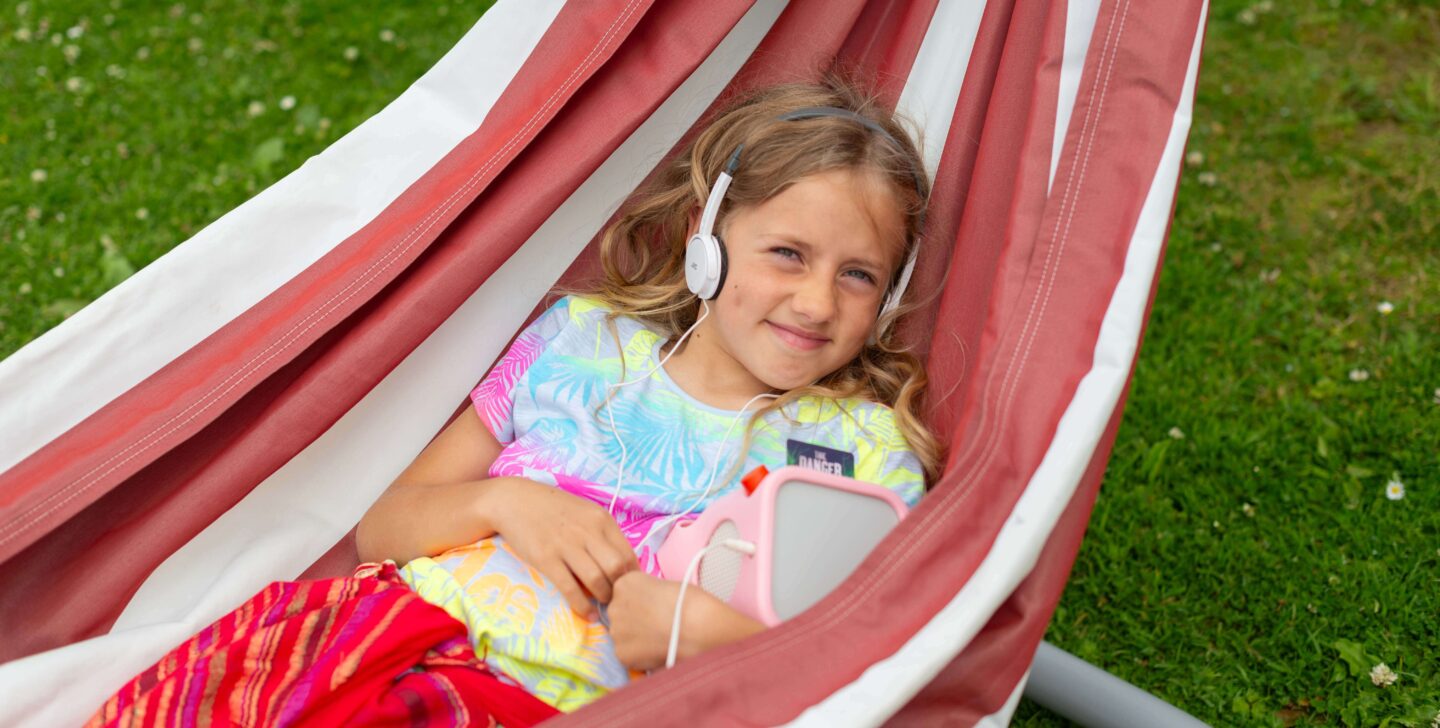 Girls in a hammock listening to audiobook on Yoto Player using headphones.